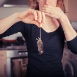 Woman with dead mouse in kitchen
