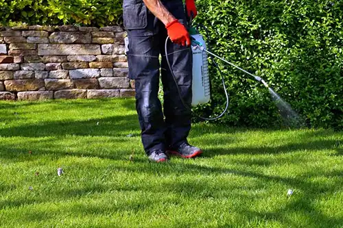 Person spraying weed killer on a lawn - Keep pests away from your lawn with Arrow Exterminators in OK